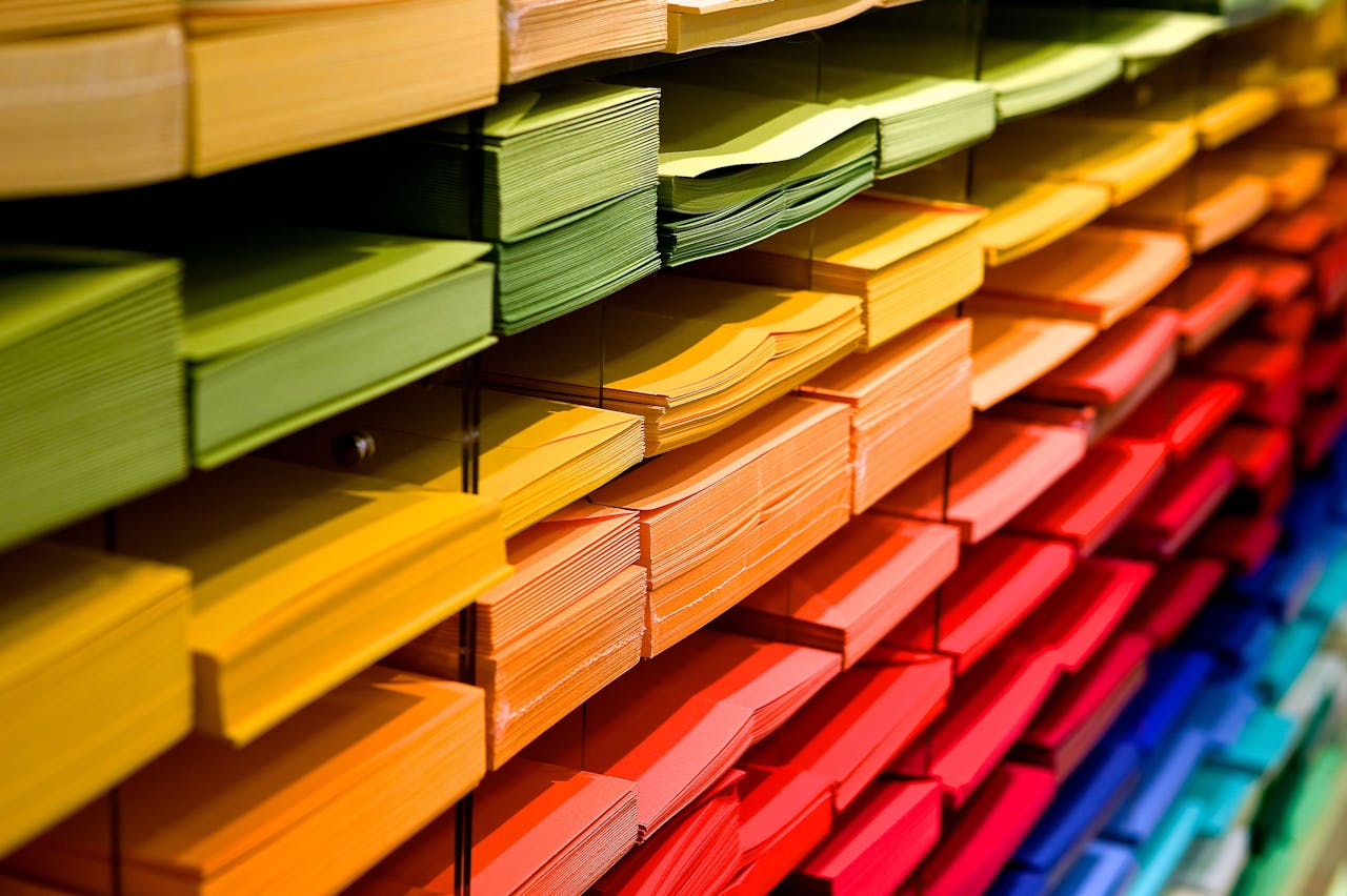 Vibrant multicolored paper stacks arranged on shelves in a stationery store.